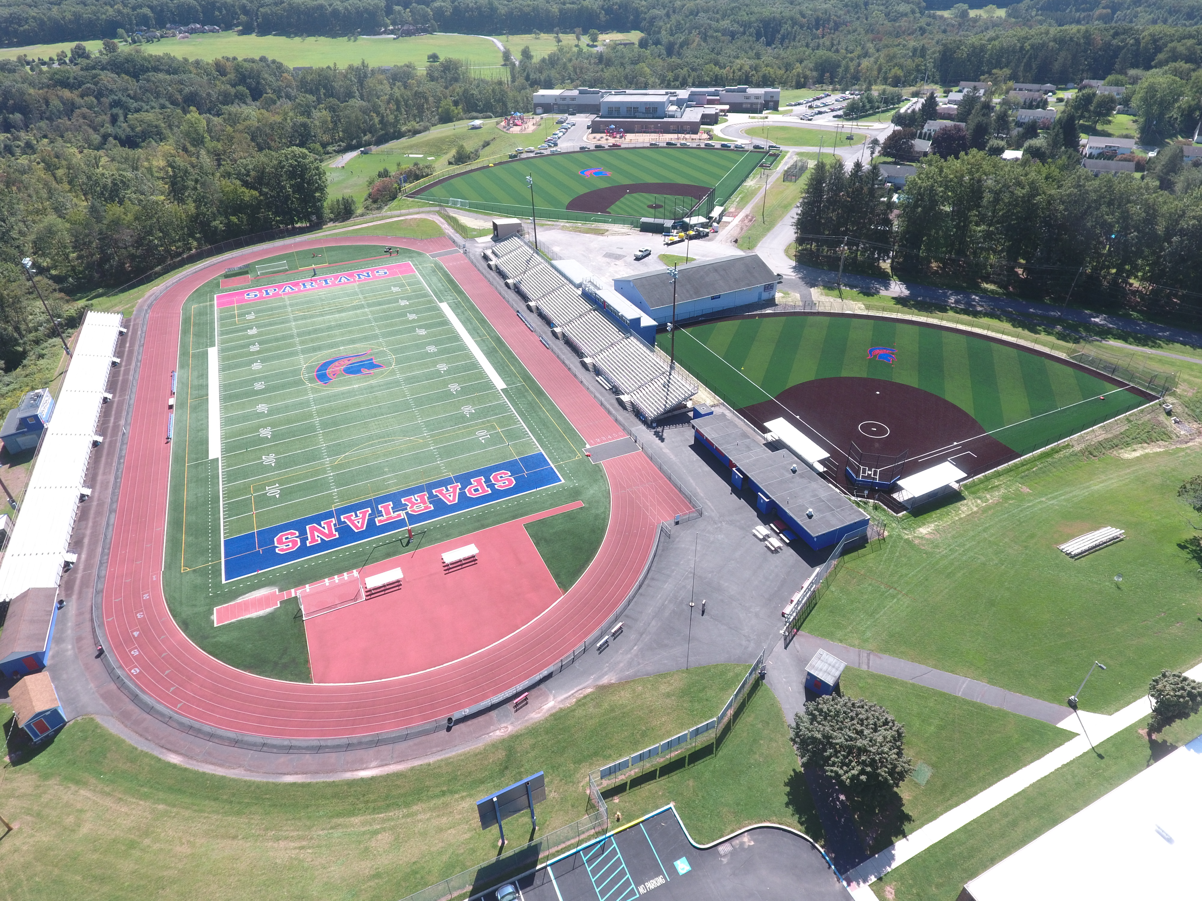 Aerial view of the North Schuylkill Spartans athletic complex, showing the football field and track, two baseball fields, and the elementary school building in the background.