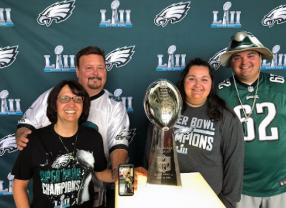 Dr. Robert Bricker poses with family in front of a Philadelphia Eagles Super Bowl LII display alongside the Vince Lombardi Trophy.