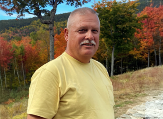 Eli Peleschak poses on an outdoor trail surrounded by autumn foliage.